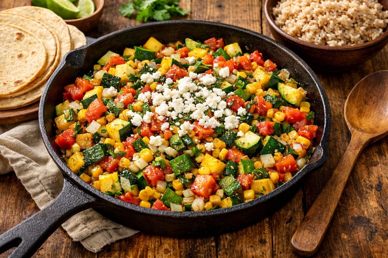 Tazón relleno de calabacitas - calabacín en trozos, calabaza amarilla, maíz y pimientos asados en una salsa ligera de tomate a la sartén